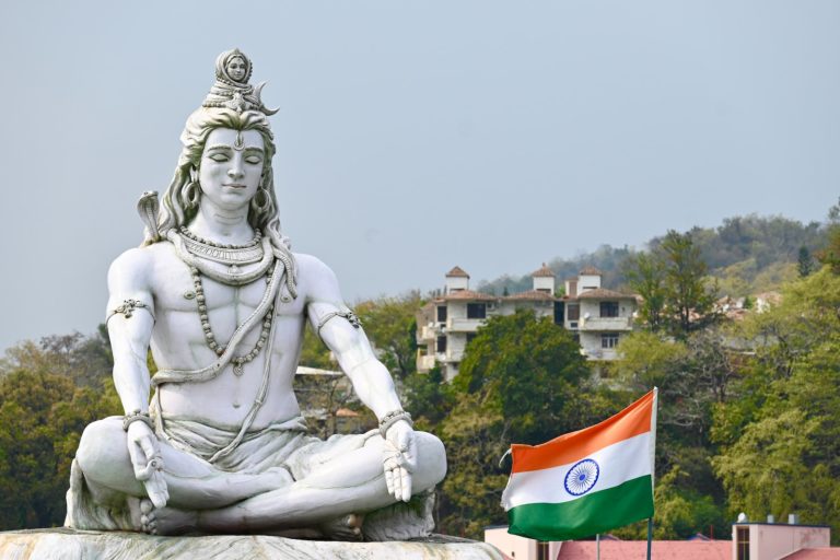 a statue of a man sitting in a lotus position with a flag in front of